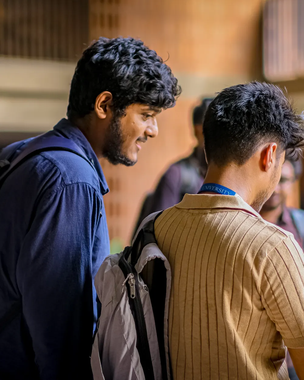 Two students in a college corridor filming on a phone gimbal.