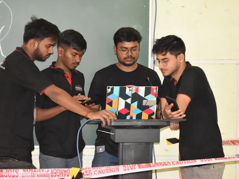 Four students gathered around a laptop, launching a project.